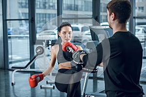 young female fighter performing low kick with trainer