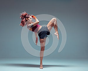 A young female fighter performs a high kick.