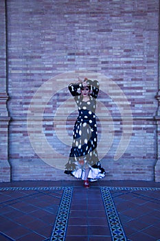 Young female flamenco artist, Hispanic and brunette, with typical flamenco dance suit in movement. Concept of flamenco, dancer,