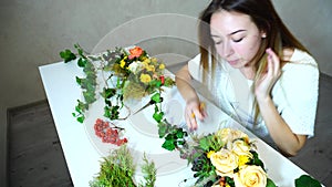 Young female flower handler keeps record of flowers and writes observation in notebook sitting at table in office.