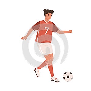 Young female football player running up to kick ball forward. Woman playing European soccer in red sports outfit, boots