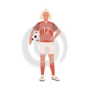 Young female football or soccer player standing and holding ball in hand. Smiling woman wearing red sports outfit, boots