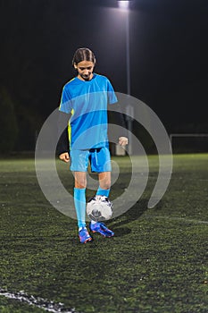 young female footballer kicking a football and running in a ground