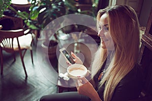 Young female freelancer chatting on mobile phone while sitting on the couch in vintage cafe