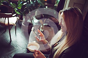 Young female freelancer chatting on mobile phone while sitting on the couch in vintage cafe