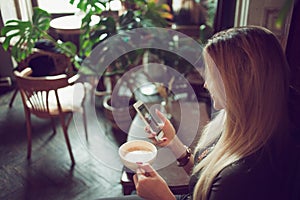 Young female freelancer chatting on mobile phone while sitting on the couch in vintage cafe