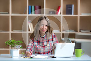 Young female Freelancer Professional working at desk in warm interior
