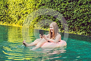 Young female freelancer sitting near the pool with her laptop in