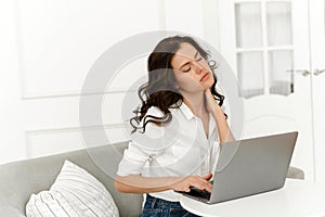 Young female freelancer working from home and experiencing neck pain. Lots of work from home