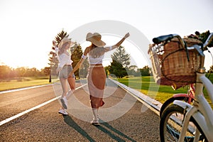 Young female friends enjoying road trip on bicycle spending weekend together