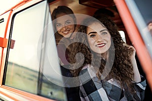 Young female friends on a roadtrip through countryside, looking out of minivan.