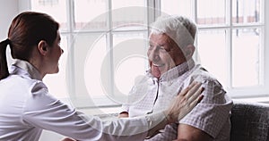 Young female general practitioner touch shoulder of smiling elderly patient.