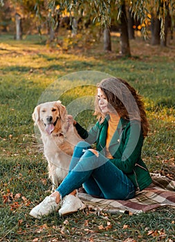 Young female girl hugging her golden retriever dog near river outdoors