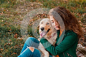 Young female girl hugging her golden retriever dog near river outdoors