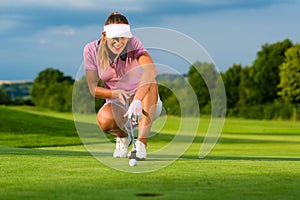 Young female golf player on course aiming for her put