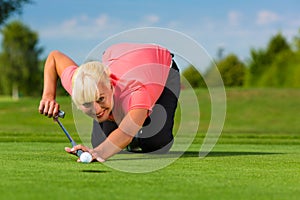 Young female golf player on course aiming for put