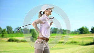 Young female golfer with club feeling lower back pain after shot, sports trauma