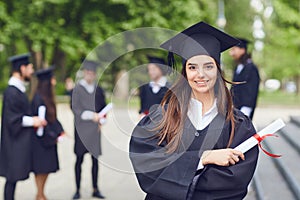 A young female graduate against the background of university graduates.