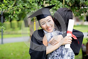 Young female graduate hugging her friend at graduation ceremony