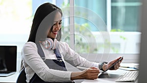 A young female Graphic designer holding stylus pen drawing on tablet.