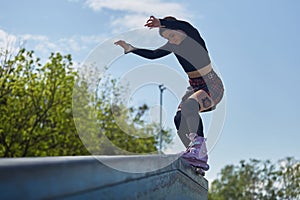 Young female grinding on a ledge in a skatepark. Aggressive inline skater athlete performing a grind trick in a outdoor skatepark