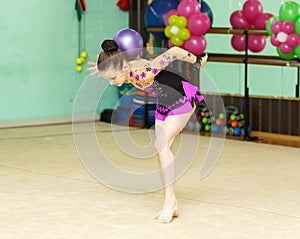 Young female gymnast doing crafty trick with ball