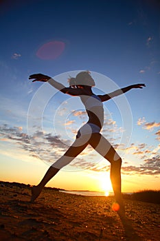 Young female gymnast exercising at sunrise