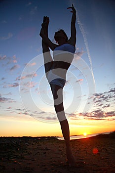 Young female gymnast exercising at sunrise
