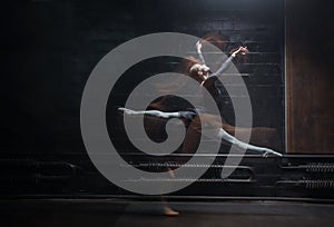 Young female gymnast showing her twine on the dark background