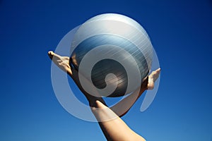 Young female gymnast with yoga ball held between legs