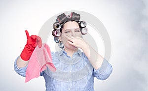 Young female in hair curlers emotionally pinches her nose with a hand from the stench.