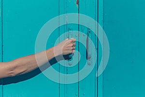 Young female hand grabbing blue door