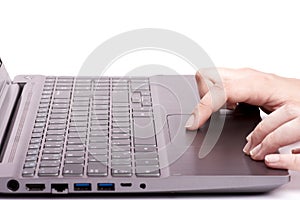 Young female hand working on a silver laptop touchpad with keyboard. Isolated on white background