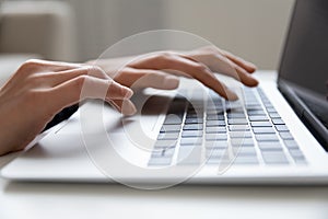 Young female hands typing on keyboard of modern laptop computer