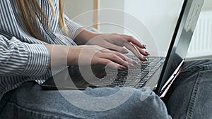 Young female hands typing on laptop keyboard, writing code. close up, side view