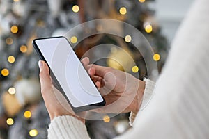 Young female hands use mobile phone, smartphone mockup with white screen. Close-up photo