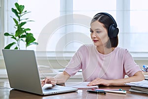 Young female in headphones using computer laptop for studying