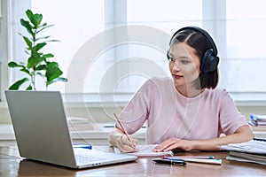 Young female in headphones using computer laptop for studying