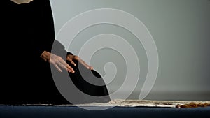 Young female in hijab praying on mat, asking god forgiveness, religious ritual