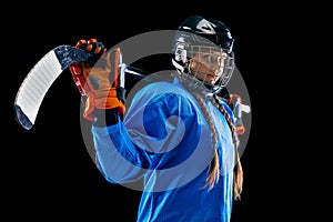 Young female hockey player with the stick isolated on black background