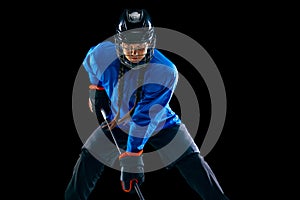 Young female hockey player with the stick isolated on black background