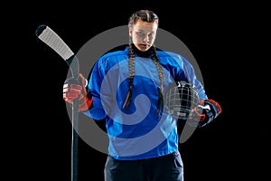 Young female hockey player with the stick isolated on black background