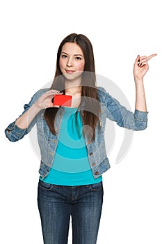 Young female holding blank credit card and pointing to the side