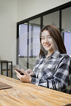 Female holding mobile phone and smiling to camera.