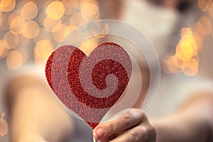 Young Female holding sparkling red heart wearing white protective medical mask for coronavirus, Covid-19 and Valentine's