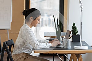 Young female indian ethnicity employee working on computer.