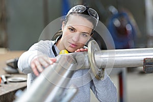 young female industrial engineer taking measures metal pipe