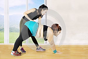 Young female instructor helps her client to exercise