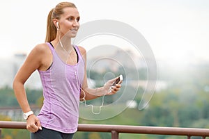 Young female joger is runing and listening to music during the run photo