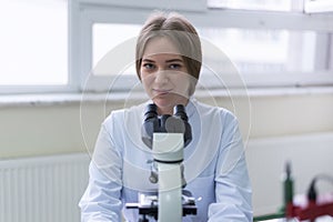 Young female Laboratory scientist working at lab with test tubes and microscope, test or research in clinical laboratory. Looking